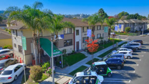 Leasing office exterior, street parking in front, meticulously groomed grounds, Photo taken on a sunny day.