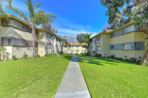Exterior sidewalk leading to residential buildings, thriving vegetation around baldwin village grounds.