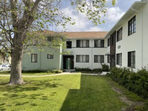 Corner perspective of buildings 4136 and 4138, highlighting the updated exterior paint, secure entry, and landscaped walkway surrounded by a spacious grassy area.