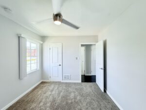 Interior Unit Bedroom, Neutral toned carpeting, white walls and doors, ceiling fan.