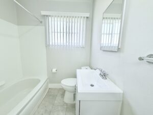 Interior Unit bathroom, white walls, white tile floor, white vanity, shower/bath.