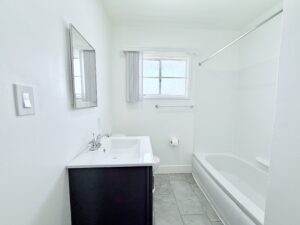 Interior Unit Bathroom, white walls, white bathroom sink with gray vanity, shower/bath, stone tile floor.