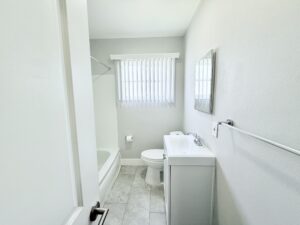 Interior Unit bathroom, white walls, white tile floor, white vanity, shower/bath.