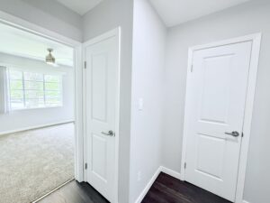 Interior Unit Hallway, Wood floors in hallway, linen closet in hallway, bedroom with carpeting, ceiling fan in bedroom.