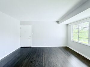Interior Unit Living Room, dark wood floors, white walls, large window.