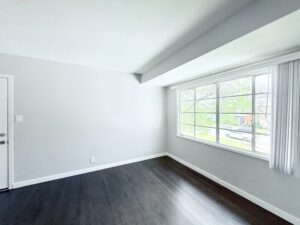 Interior Unit Living Room, dark wood floors, white walls, large window.