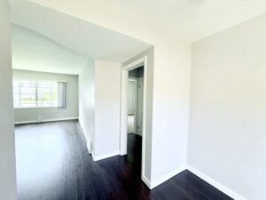 Interior Unit Hallway, Dark brown wood floors, neutral toned walls, large living room.